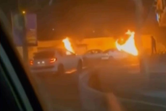 Iranian state television images showing cars driving past burning vehicles in Tehran