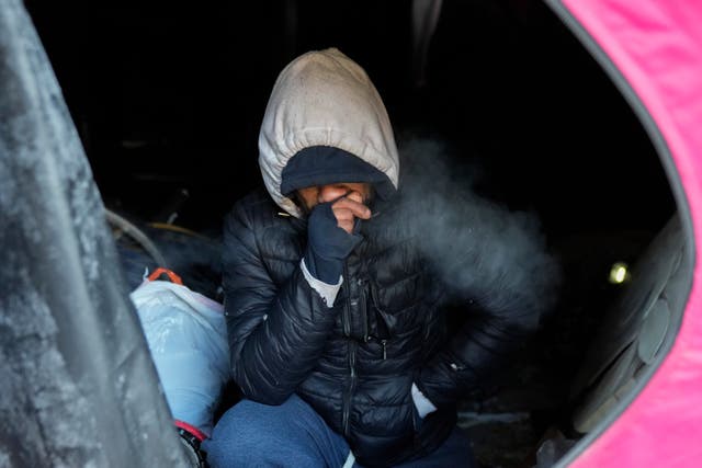 Romeo Garcia blows warm air on his hand inside his tent as Orange Tent Project nonprofit workers distribute supplies to unhoused people during dangerously cold temperatures in Chicago