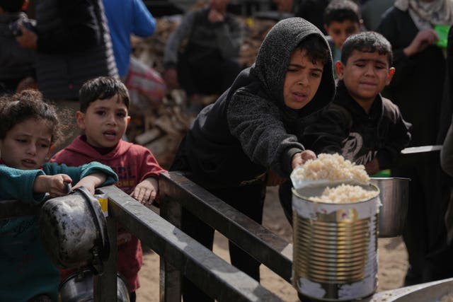 Palestinian children receive donated food at a community kitchen in Nuseirat, in central Gaza