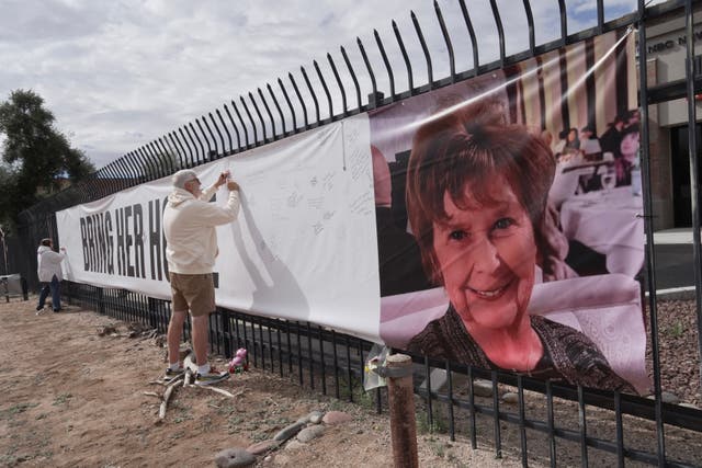 A man signing a banner supporting Nancy Guthrie