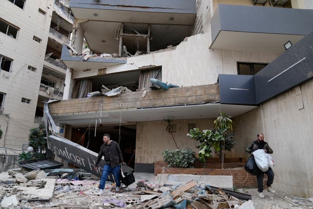 Hotel guests carry their belongings, as they leave a damaged hotel that was hit by an Israeli airstrike in Hazmieh east of Beirut
