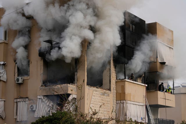 Rescue workers inspect an apartment damaged in an Israeli airstrike as thick smoke fills the building in the southern port city of Sidon, Lebanon