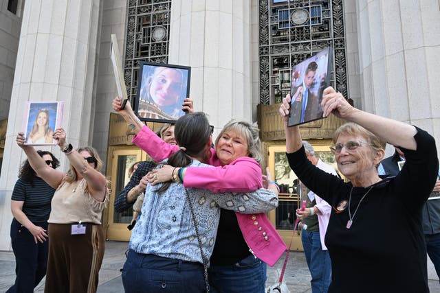 Lori Schott, second from right, holds up a photo of her daughter Annalee Schott, beside others after the verdict in a landmark trial over whether social media platforms deliberately addict and harm children at Los Angeles Superior Court