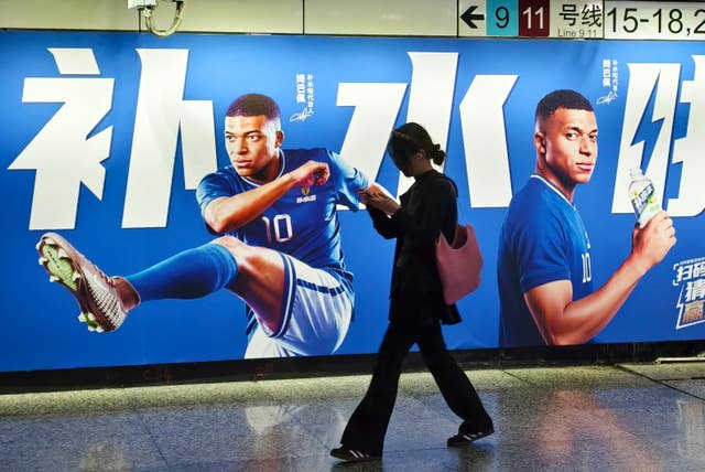 A woman walks by an advertisement featuring Kylian Mbappe in Shanghai, China
