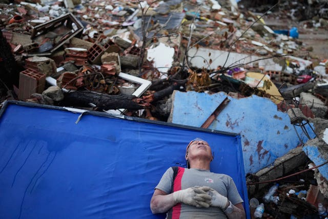 A resident takes a break amid the rubble while searching for their nephews at a building that collapsed during the earthquakes that struck La Guaira
