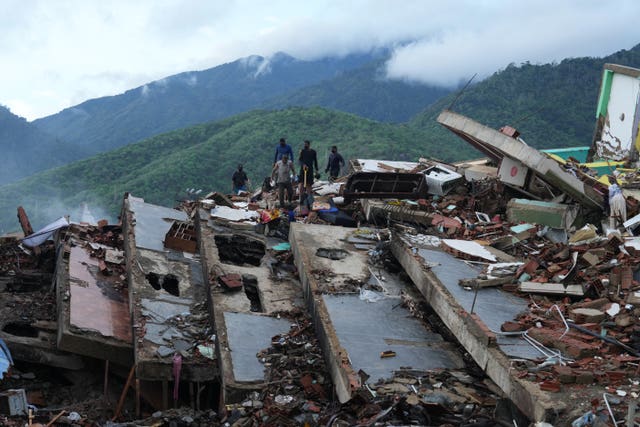 Residents search through the rubble of a building that collapsed in the earthquakes in La Guaira