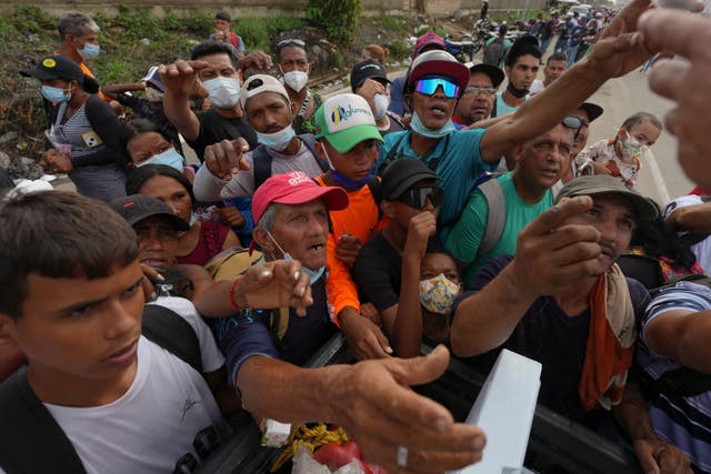 People reach out to receive supplies from volunteers, days after an earthquake struck La Guaira