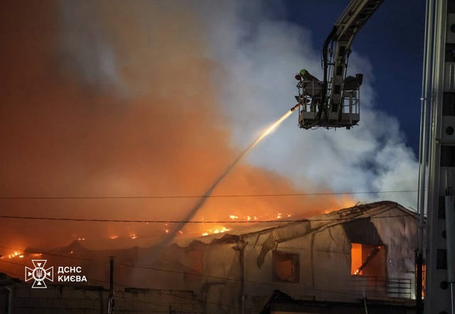 Emergency services personnel work to extinguish a fire following a Russian air attack in Kyiv, Ukraine