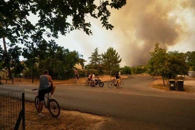 People watch massive plumes of smoke caused by wildfires in western France