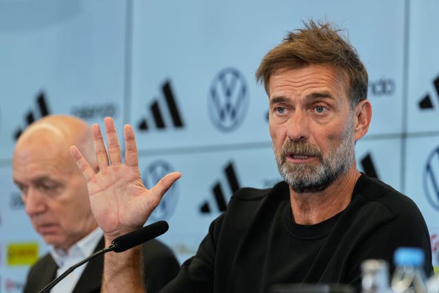 New Germany head coach Jurgen Klopp raises his right hand during a press conference