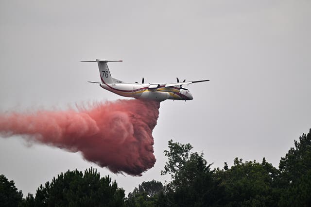 A De Havilland Canada DHC-8-400 Dash 8 operated by the French civil defence agency drops fire retardant as wildfires rage near Marcheprime, outside Bordeaux, France