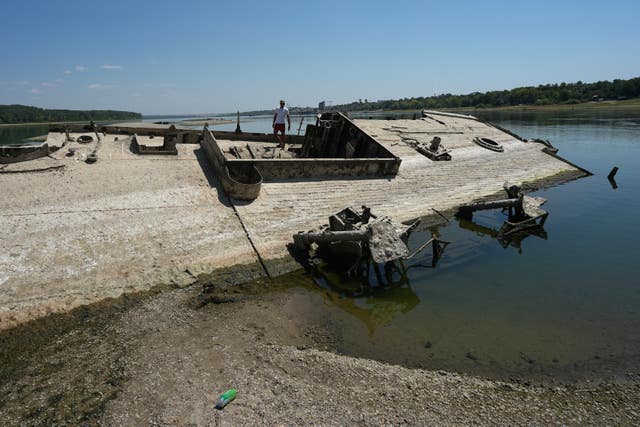 A man walks on the wreckage of a Second World War German warship, emerged due to the drought, in front of Djerdap II, a large dam on the Danube River, between Romania and Serbia, near Prahovo, Serbia
