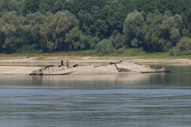 A man takes a photo on the wreckage of a Second World War German warship, emerged due to the drought, in front of Djerdap II, a large dam on the Danube River, between Romania and Serbia, near Prahovo, Serbia