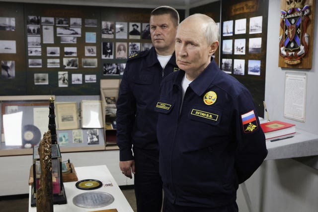 Russian President Vladimir Putin, right, listens to a navy officer during a visit to the Varyag missile cruiser