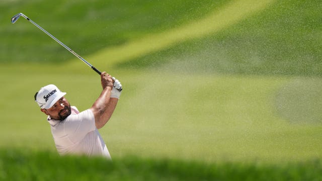 JJ Spaun hits from a bunker up to the 18th green