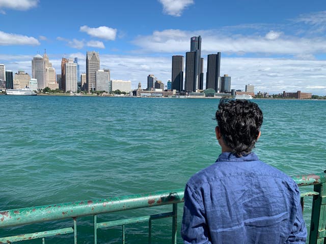 A person looks at the Detroit skyline across the Detroit River in Ontario