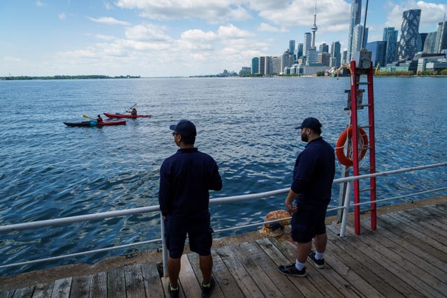 People look out across Lake Ontario and the Toronto skyline from the Toronto Harbour in Toronto
