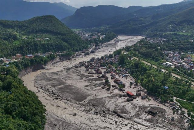 Damaged houses stand precariously near the swollen, debris-choked banks of the Trishuli River after flash floods in Nepal’s Nuwakot district