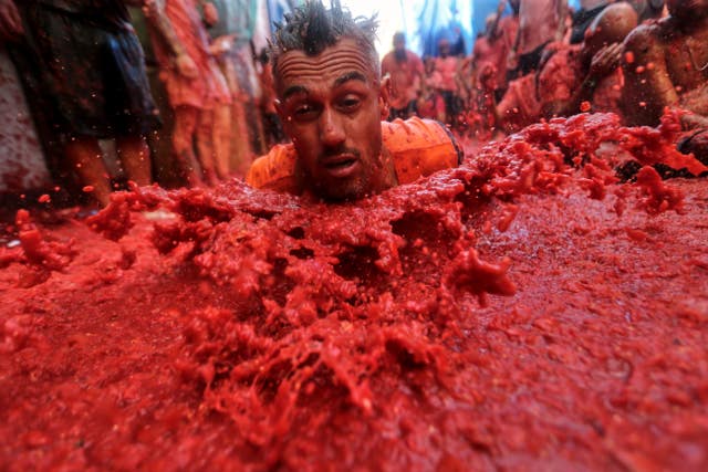 A man throws himself over a pool of tomatoes during the annual “Tomatina” tomato fight fiesta, in the village of Bunol near Valencia, Spain