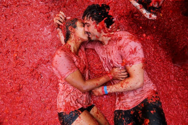 A couple kisses during the annual “Tomatina” tomato fight fiesta, in the village of Bunol near Valencia, Spain