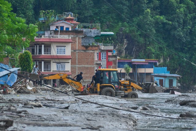 Rescuers use earthmovers to reach submerged houses after flash flooding along the Trishuli River in Nepal’s Nuwakot district