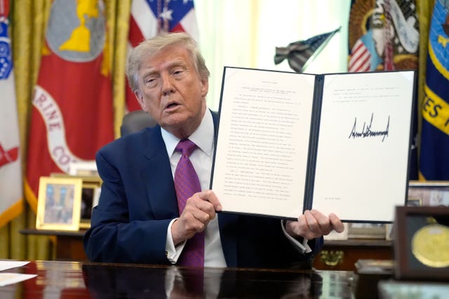 US President Donald Trump holds up a signed executive order in the Oval Office of the White House