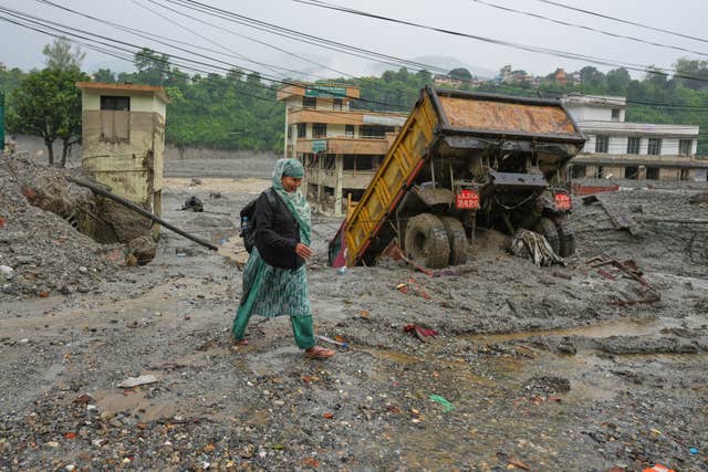A woman walks through mud and debris left behind by flash flooding in Nepal’s Nuwakot district