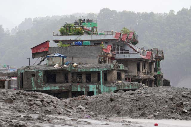 A damaged house stands amid debris of flash flooding in Nuwakot district in Nepal on Saturday