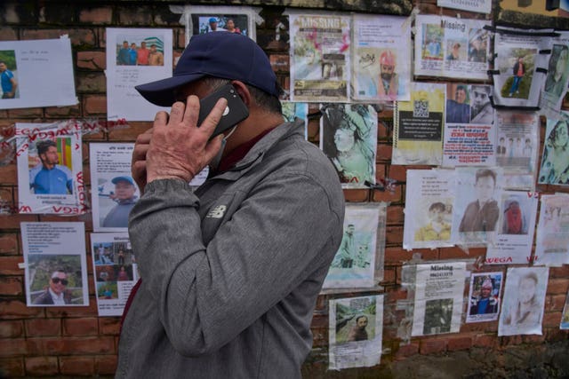 A man talks on his mobile phone after looking at photographs of people missing following the flash floods