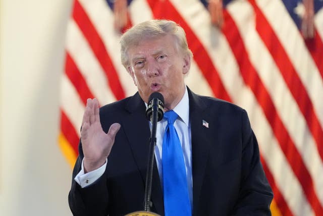 President Donald Trump gestures while speaking in front of the US flag
