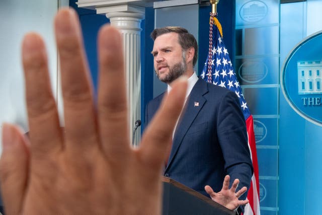 A reporter raises their hand as they seek to ask JD Vance a question