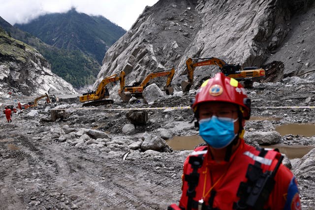 A rescue worker stands near excavators