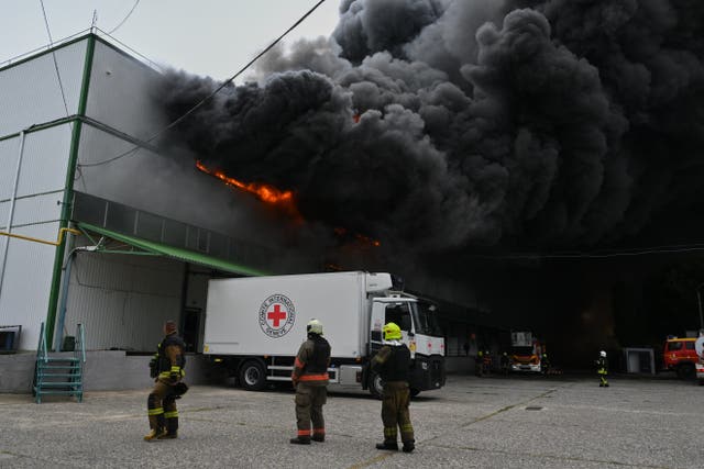 Firefighters tackling a large blaze, with huge black smoke rising from it