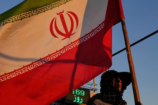 A woman holds an Iranian flag as part of a pro-government campaign in downtown Tehran
