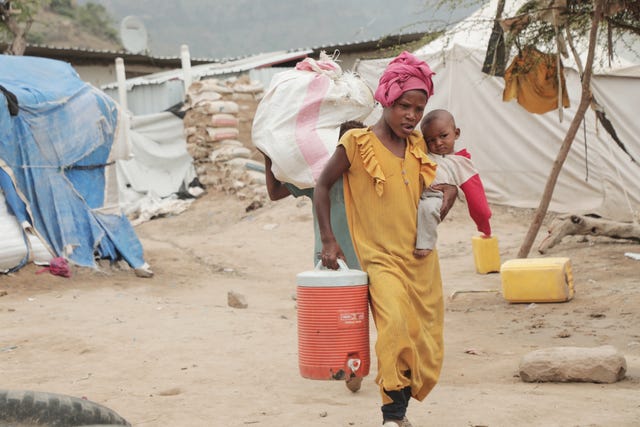 A woman carries a baby and water