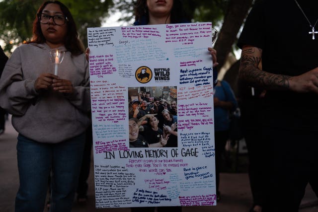 Allyson Silva holds a memorial board for her co-worker Gage Weida
