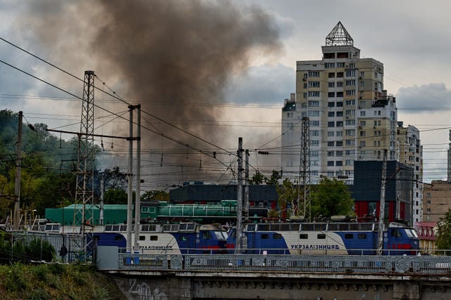 Trains stand on railway tracks as a city market burns nearby following a Russian drone attack in Kyiv