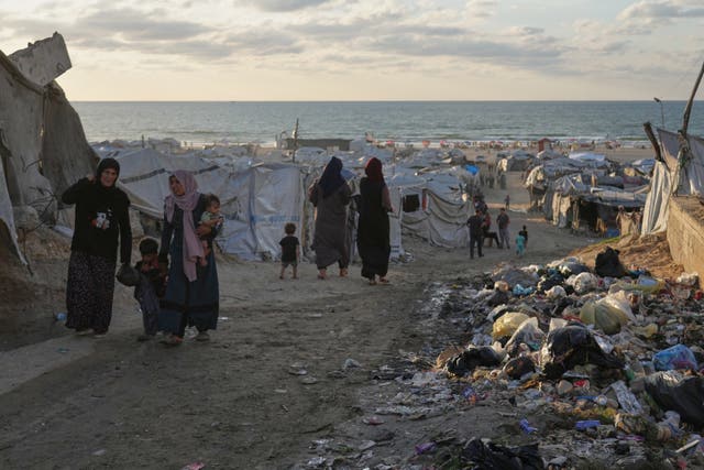 Women walking amongst tents and rubbish
