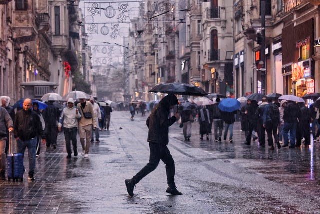 Pedestrians walk along Istiklal main street under heavy rain in Istanbul