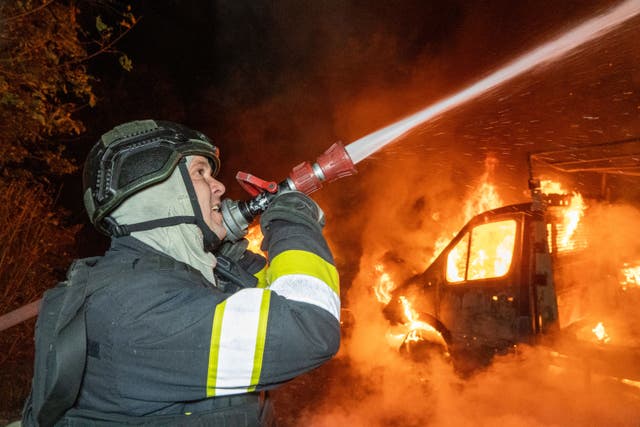 A rescue worker tries to put out a fire at a house damaged in a Russian drone strike on Kharkiv, Ukraine