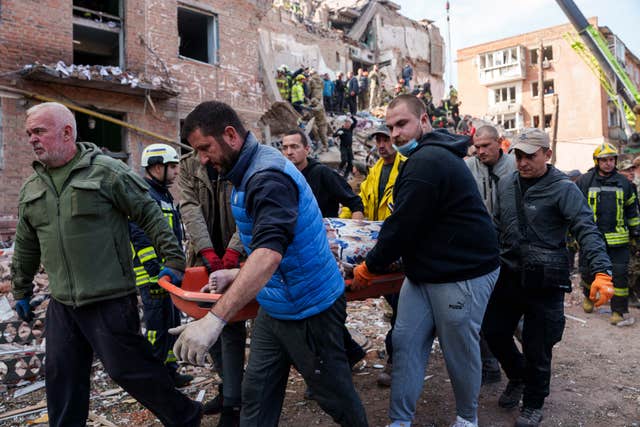 Locals carry the body of a person, killed in a Russian missile strike on a residential building, in Pryluky, Ukraine