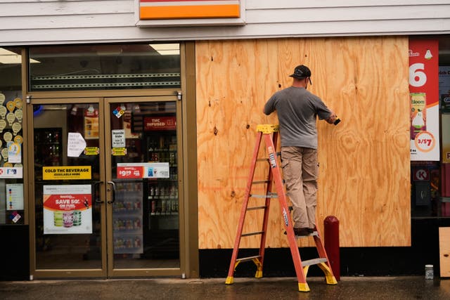 Man boarding up a US convenience store