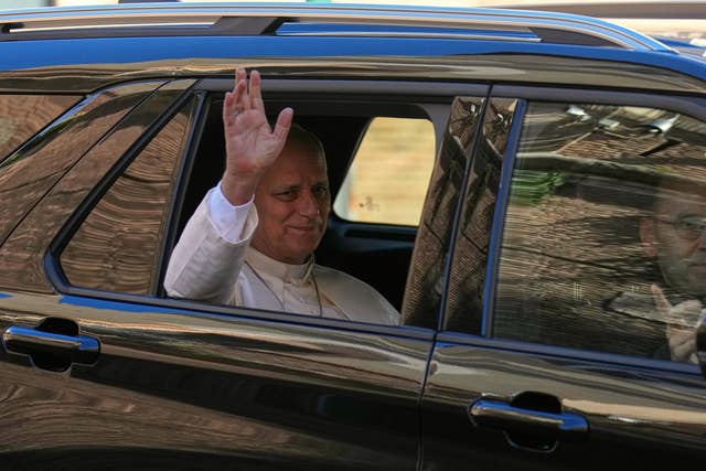 Pope waves out of the window of a car