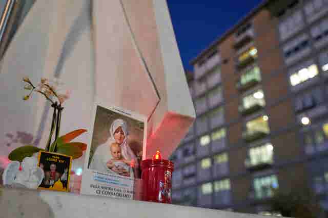 An image of Pope Leo rests at the base of a statue of late pope John Paul II outside the hospital where Leo had surgery