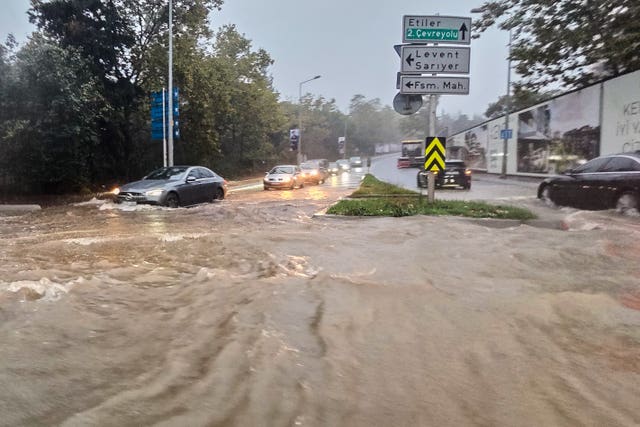 Vehicles drive along a partially flooded road during heavy rain