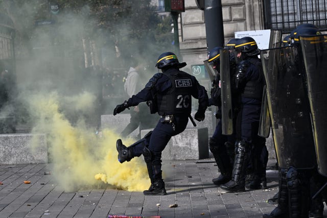 A policeman kicks a tear gas canister