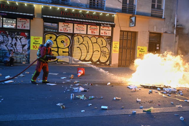 A firefighter extinguishes a fire during clashes with police in Paris