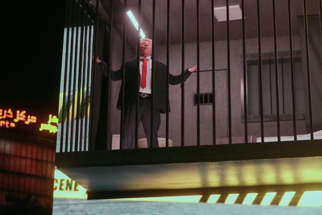 An actor portraying Donald Trump sits behind bars in a billboard installation resembling a prison cell in Tajrish Square in Tehran