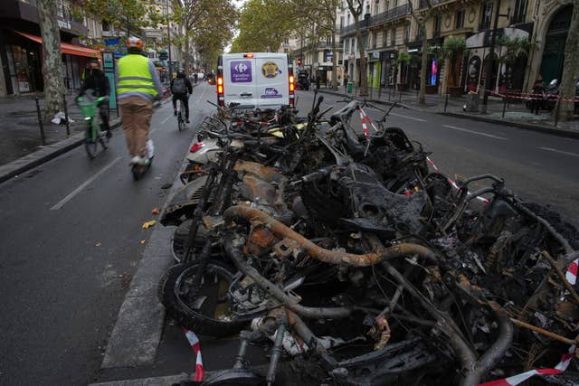 People ride past burned-out bikes in Paris