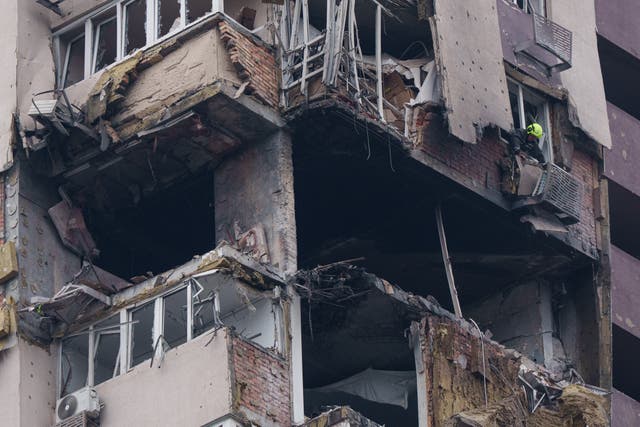 A rescue worker clears rubble from a multi-storey residential building damaged in a Russian drone strike in Kyiv, Ukraine
